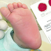 Um pezinho de recém nascido, com os dedos de uma mão com luvas brancas cirúrgicas e teste ao lado