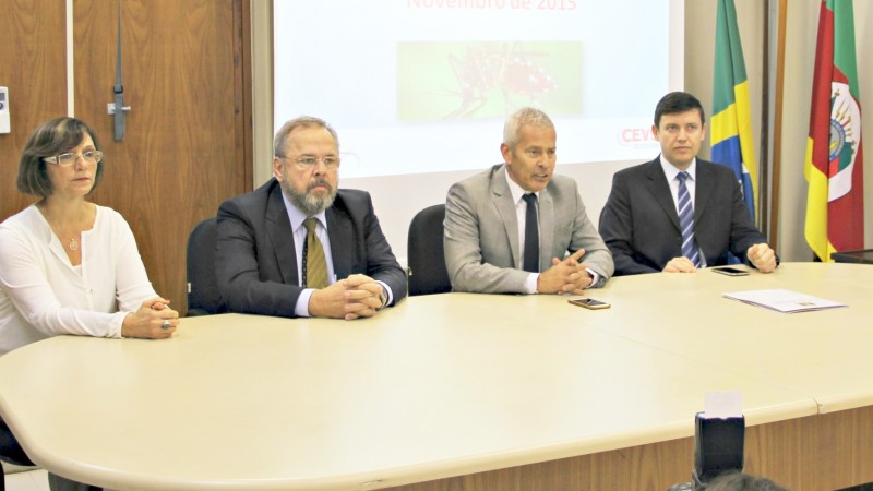Atrás de uma mesa oval, estão sentados a diretora Marilina; os Secretários Paz e Gabbardo e mais um homem.