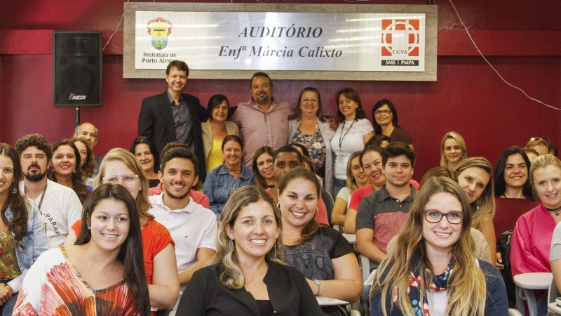 Um grupo de pessoas, de pé ou sentadas, olha pra frente e sorri.