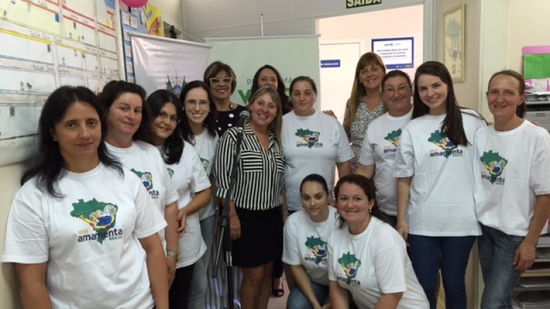 A imagem mostra um grupo de mulheres, de pé ou abaixadas. A maioria está com a camiseta do Amamenta Brasil.