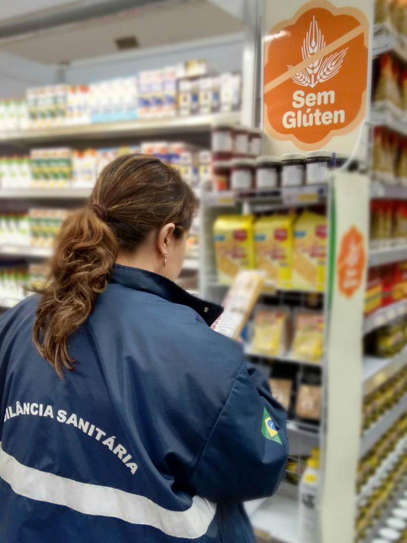 Uma fiscal da vigilância sanitária observa produtos em prateleiras de um supermercado.