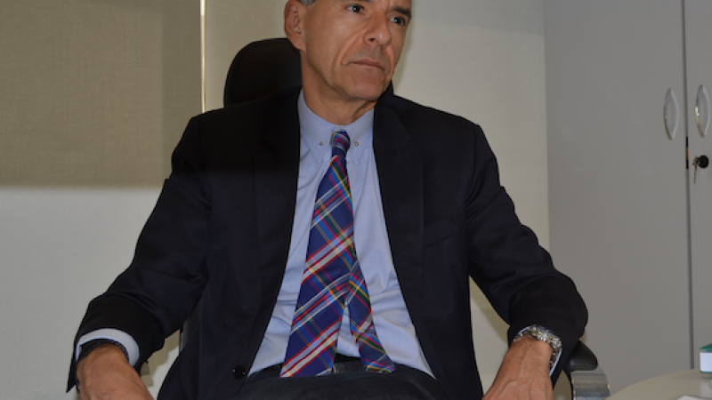Sentado, Arnaldo olha para o lado.