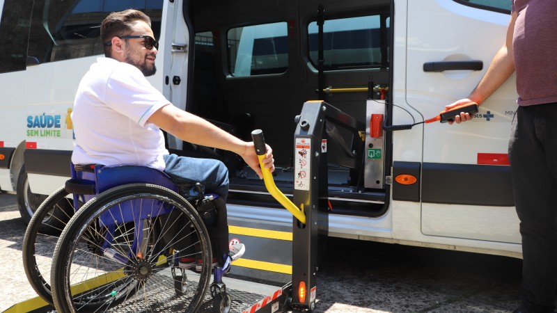 Um cadeirante manuseia o elevador para entrar numa van. 