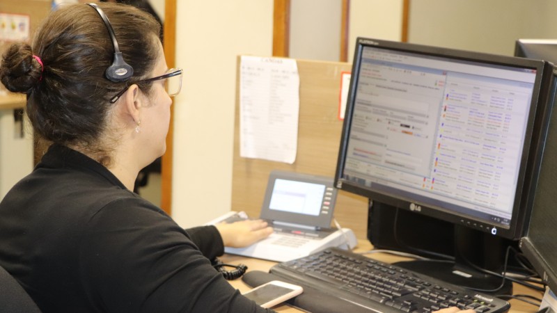 Uma atendente trabalha, sentada na frente do computador.