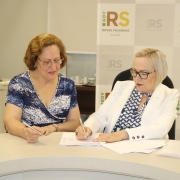 SEcretária Arita assina documento sentada ao lado de Eliane.