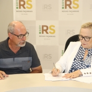 Secretária Arita assina documento sentada ao lado de Marcos.