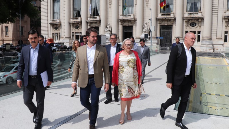 Secretária Arita, Governador Leite, chefe da Casa Civil Otomar Vivian e outras pessoas caminham em frente ao Palácio Piratini.