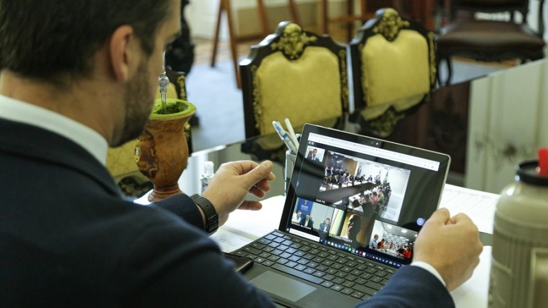 Governador Leite olha para a tela do notebook onde passa a videoconferência.
