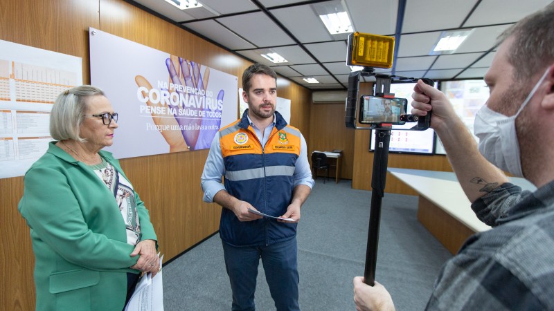 Governador e secretária em frente a uma câmera sendo filmado