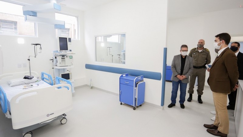 Governador Leite e mais três homens, todos de pé e de máscara, visitam e observam lavanderia.