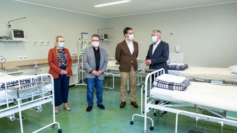 Sperotto fala enquanto Arita, Ranolfo e Leite ouvem. Os quatro estão de pé e de máscara dentro da UTI.