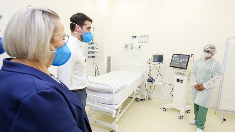 Secretária Arita e Governador Leite assistem a demonstração de um aparelho por uma profissional de saúde. 