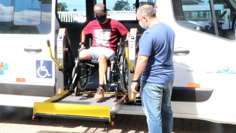 Cadeirante sobe em veículo adaptado com plataforma.