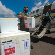 Um funcionário segura uma caixa grande de isopor para colocar no avião. Outras caixas esperam no carrinho. 
