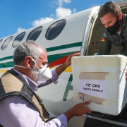 Um funcionário passa, para outro, uma caixa grande de isopor para colocar no avião.  