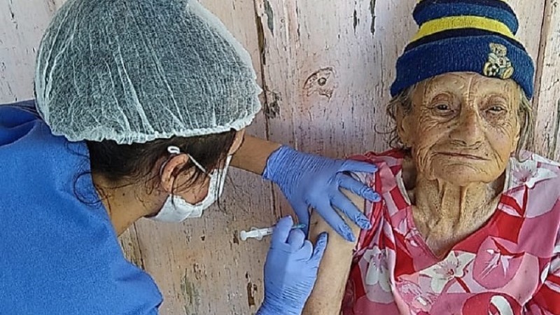 Uma profissional vacina uma idosa.
