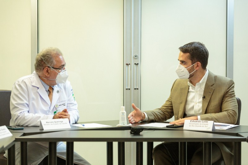 Ministro Queiroga e Governador Leite conversam, sentados atrás de uma mesa. Os dois estão de máscara.