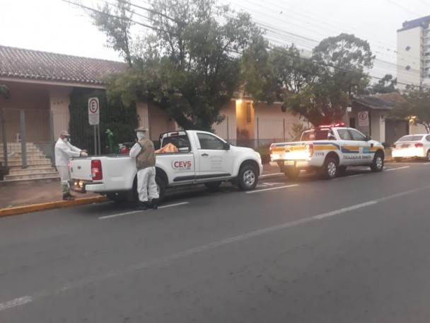 Dois funcionários uniformizados mexem em equipamentos que estão na caminhonete do CEVS.