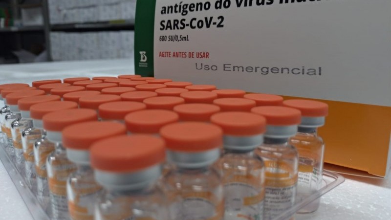 cerca de 40 frascos de vacinas coronavac em frete à caixa com o nome do antígeno SARS-CoV-2