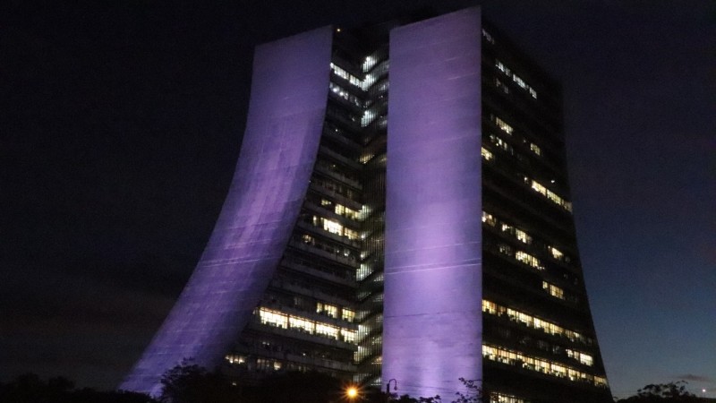 Imagem noturna do Centro Administrativo iluminado de lilás.