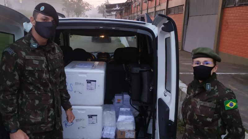 Um militar e uma militar na porta de um veículo com as caixas de medicamentos 