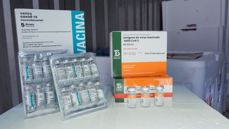 A imagem mostra caixas e frascos de vacinas em cima de uma superfície.