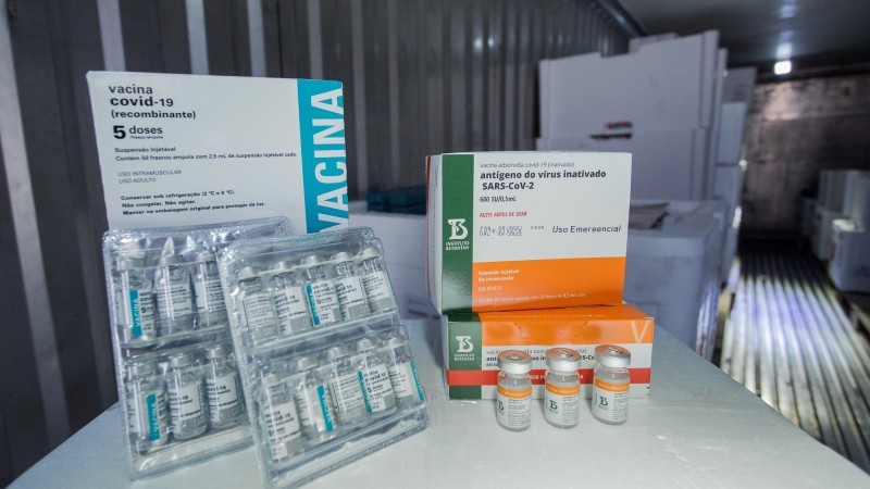 A imagem mostra caixas e frascos de vacinas em cima de uma superfície.