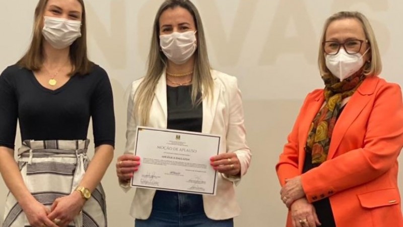 Secretária Arita ao lado de duas vacinadoras da região. Uma está com o certificado na mão. As três estão de pé e de máscara.