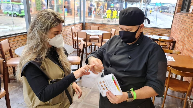 Mulher entrega material para um profissional de restaurante.