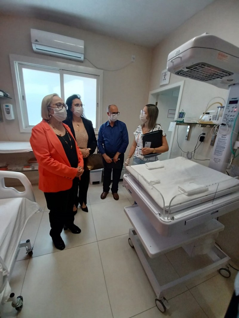 Secretária Arita e mais três pessoas (duas mulheres e um homem) observam equipamentos e cama do hospital.