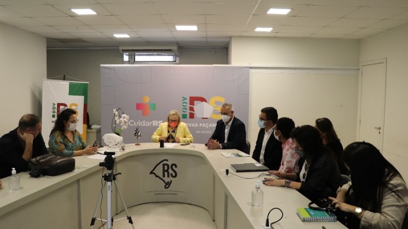 Secretária Arita e participantes da reunião conversam. Todos estão sentados atrás de uma mesa em formato de U.