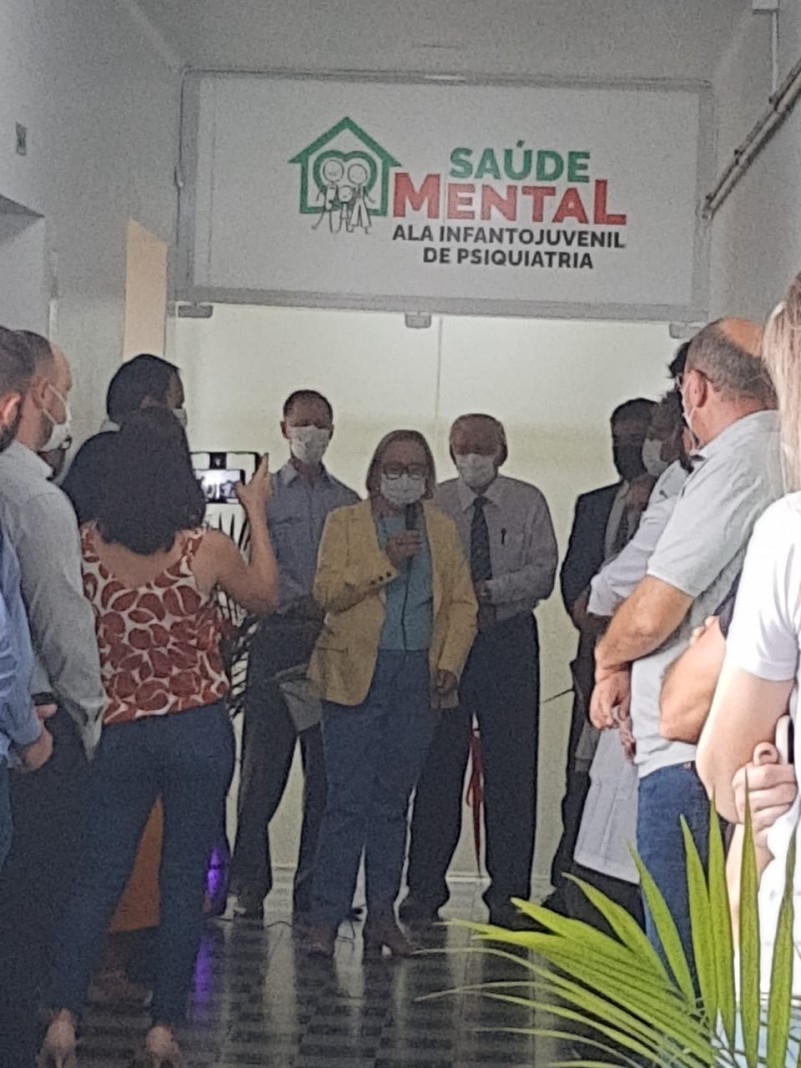 A Secretária Arita discursa segurando o microfone dentro de um corredor da Santa Casa.