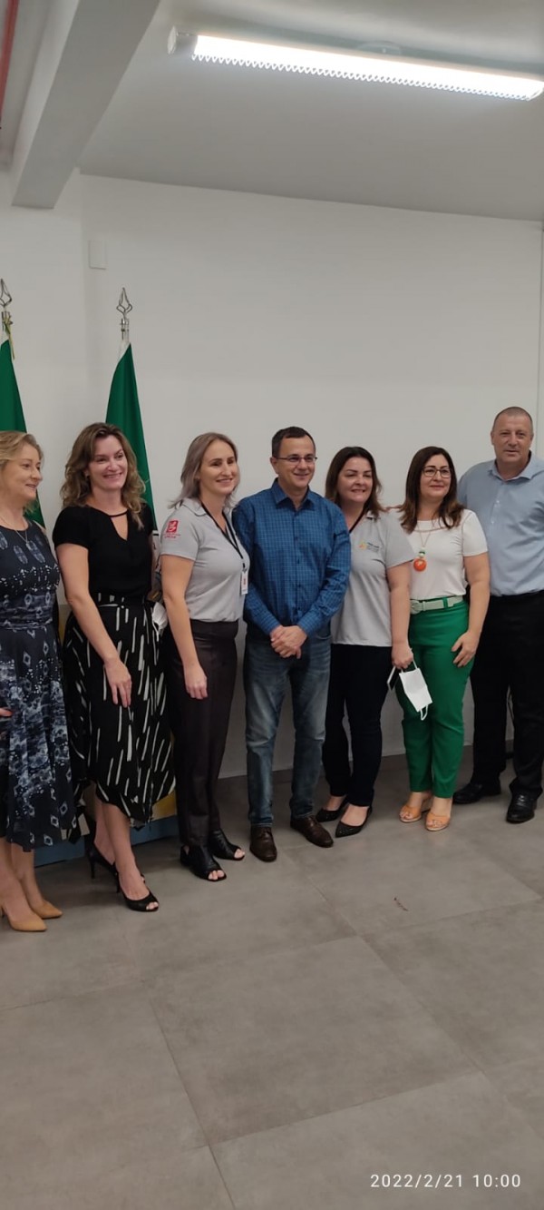 A imagem mostra um grupo de pessoas (cinco mulheres e dois homens) de pé e sorrindo.