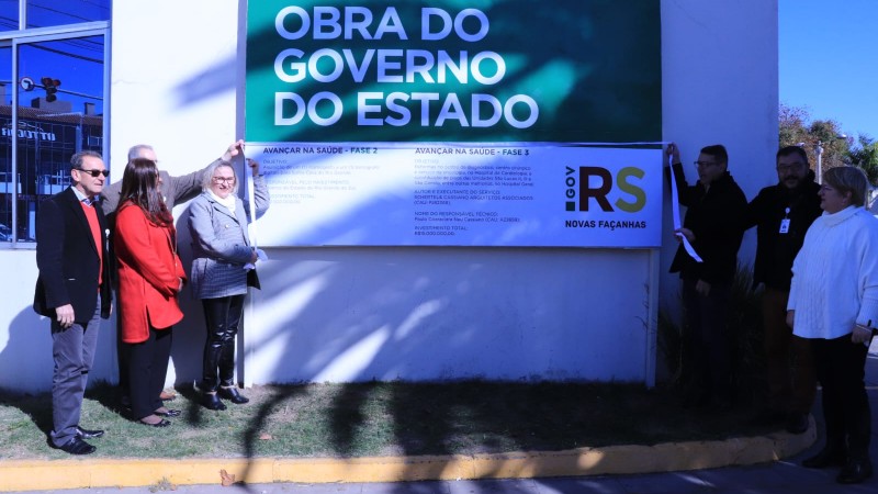 A Secretária Arita, ao lado de uma placa do projeto Avançar, acompanhada de seis pessoas. Todos estão de pé.