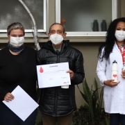 Elizio Brasil Flores, no centro de duas mulheres, ao lado da equipe do Hemocentro.