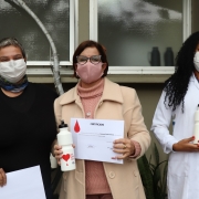 Gilmara Pires Somacal, no centro de duas mulheres, ao lado da equipe do Hemocentro. 
