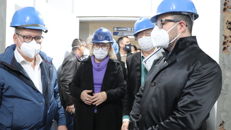 O Governador Ranolfo, a Secretária Arita e mais algumas pessoas estão de pé e de capacete na parte interna do hospital. 