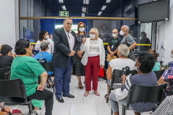 De pé, a Secretária Arita conversa com as pesoas que estão sentadas. 