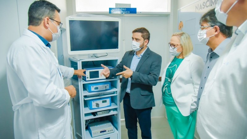 Um profissional de jaleco e máscara mostrando um apaelho hospitalar para o
outras 4 pessoas.