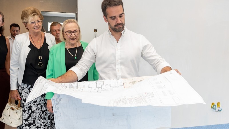 Leite observa mapa, do lado da Secretária Arita e de outra mulher. Ao fundo, mais três pessoas observam. Todo estão de pé.