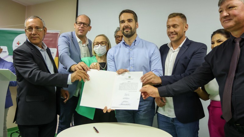 Autoridades, com governador ao centro, mostram documento assinado.