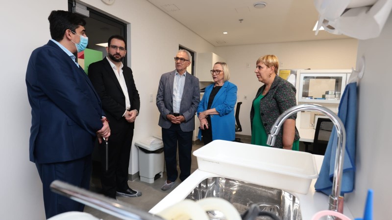 Secret&aacute;rias Arita e Ana Costa e tr&ecirc;s homens conversam dentro da institui&ccedil;&atilde;o. Um dos homens est&aacute; de m&aacute;scara. Todos est&atilde;o de p&eacute;. 