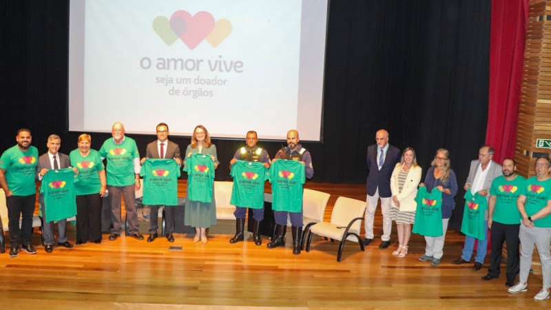 Um grupo de pessoas no palco com as camisas verdes da camapnha O amor Vive