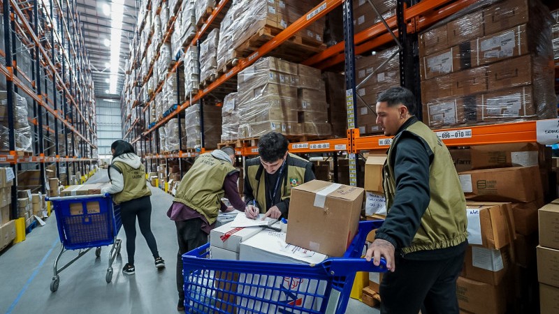Pessoas transportando caixas dentro de um depósito durante atividade em parceria com rede de farmácias para auxiliar na distribuição ágil de itens de saúde doados