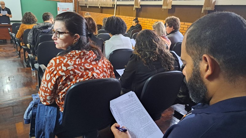 Pessoas em uma sala-auditório lendo as propostas da conferência 