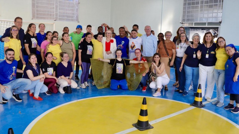 um grupo de cerca  30 pessoas em um ginásio na parte central tem uns cones de marcação