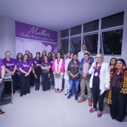 Um grupo de pessoas com camisas lilás  e outras com adereços indígena com a secretária Arita Bergmann discursando na recepção do serviço SER Mulher