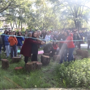 O jardim com várias plantas e árvores está repleto de participantes do evento. Autoridades que participaram da inauguração seguram fita e sorriem.