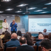 A foto mostra a secretária adjunta da Saúde, Ana Costa, falando no microfone ao lado da diretora do Dgae, Lisiane Fagundes