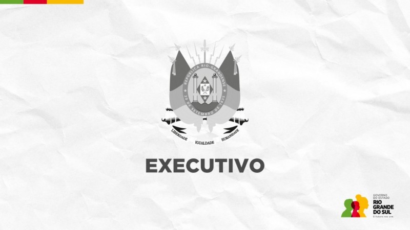 Imagem institucional em fundo branco com textura de papel amassado, trazendo ao centro o bras&atilde;o do Estado do Rio Grande do Sul em tons de cinza. Logo abaixo, aparece a palavra &ldquo;EXECUTIVO&rdquo; em destaque, em tipografia robusta e escura. No canto superior esquerdo h&aacute; pequenas faixas coloridas (verde, vermelho e amarelo) e, no canto inferior direito, o logotipo do Governo do Estado do Rio Grande do Sul, acompanhado do slogan institucional. O conjunto transmite car&aacute;ter oficial e governamental, com est&eacute;tica s&oacute;bria e formal.
